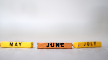 Wooden block calendar with focus on JUNE, May July blur. silver background