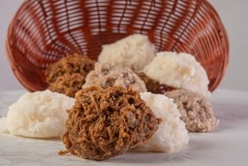 Brazilian cocada (coconut candy) dropped from a basket on a table with white towel, selective focus.