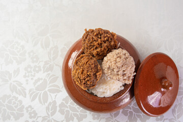 Brazilian cocada (coconut candy) placed in a ceramic pot on a table with white tablecloth, top view.