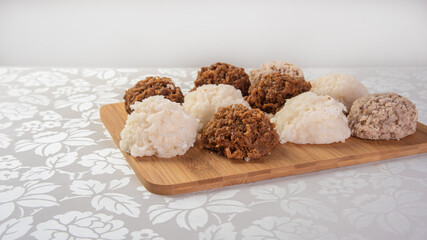 Brazilian cocada (coconut candy) placed on a polished board on a table with white towel, selective focus.