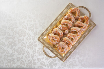sugar-coated sweet cookies placed on a golden tray on a table with white tablecloth, selective focus.