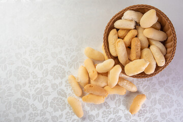 Traditional Brazilian starch biscuit called biscoito de polvilho in a basket on a table covered with white tablecloth, Top view