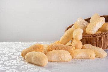 Traditional Brazilian starch biscuit called biscoito de polvilho in a basket on a table covered with white tablecloth, selective focus.