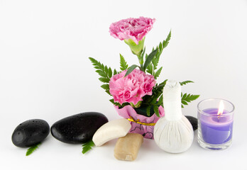 Flower vases, wood, stone massage, herbal compress, herbal soaps and candles placed on a white background.