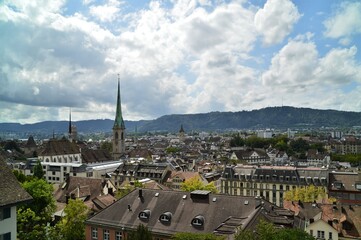 House roofs of Zurich with Predigerkirche and Grossm&uuml;nster on a summer day with white clouds