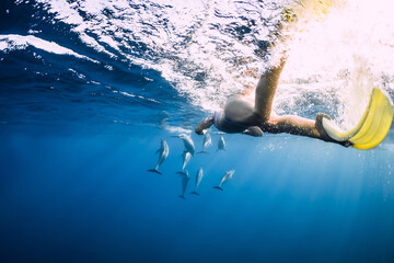Young woman swim underwater with spinner dolphins in ocean at Mauritius