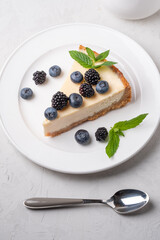 Cake cheesecake with fresh berries, blueberries and blackberries and mint in a circular plate on a gray background.