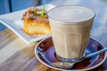 A cup of coffee latte and delicious greek pastry desser.t galaktoboureko on a wooden backround