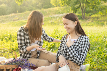 Summer holidays and vacations. Two young girls on a picnic eating, drinking lemonade, having fun in nature