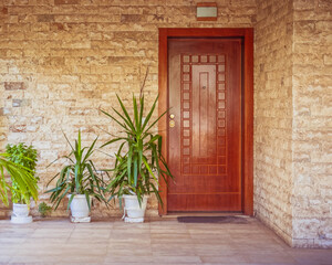 Fototapeta na wymiar contemporary stonewall house with wooden entrance door and flowerplants, Athens Greece