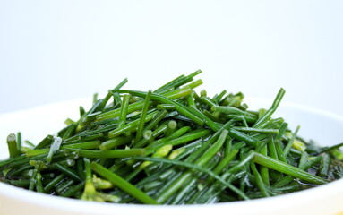 Close up stir fried  Chinese chives flowers or Allium tuberosum on white dish.