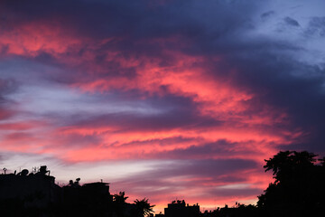 Colorful clouds and city silhouette at sunset