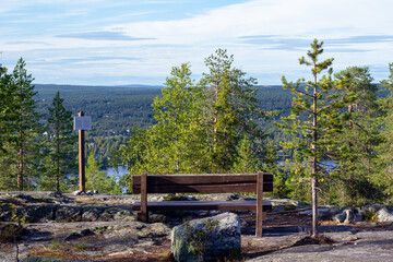 A bench on top of a hill with a view into the distance on a summer day.