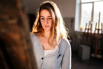 
the artist is working on a canvas in her room with windows