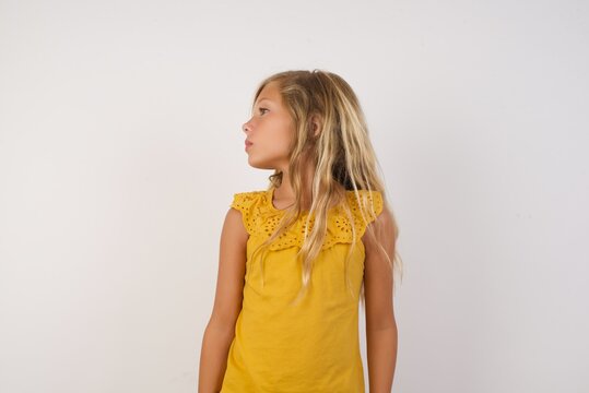 Close up side profile photo Little girl with beautiful blonde hair over white background ready to have a walk.
