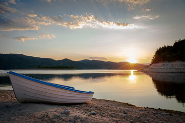 Obraz premium Sunset over a dam in Bulgaria with a white fishing boat