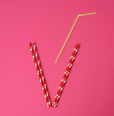 paper multicolored cocktail tubes on pink background