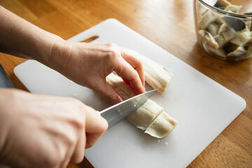 Fototapeta na wymiar Woman cutting fresh fish fillet in domestic kitchen