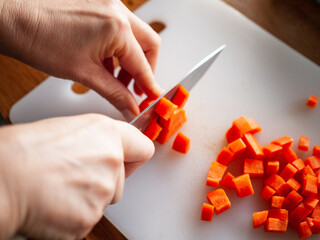 Woman cutting carrot in domestic kitchen
