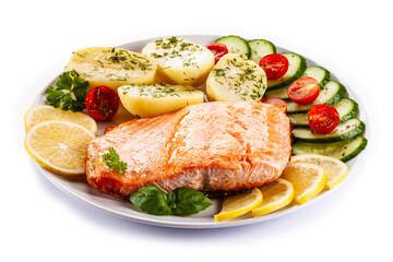 Fried salmon steak with potatoes and vegetables on white background