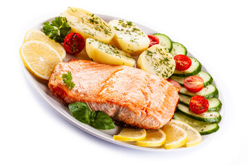 Fried salmon steak with potatoes and vegetables on white background