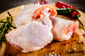 Raw chicken thighs on cutting board on wooden table
