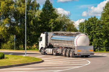 White truck with chrome tanker on a roundabout road © graja