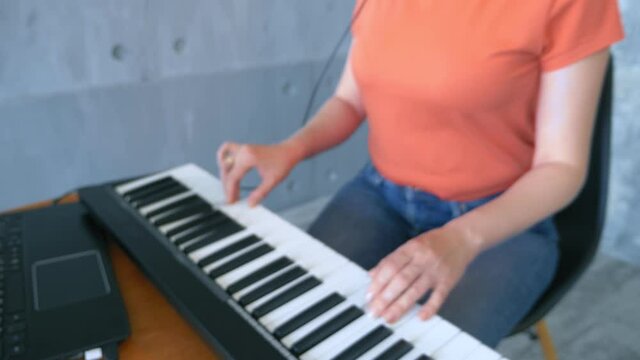 woman produces electronic music in the studio with a laptop and midi keyboard