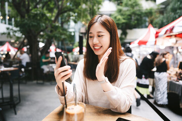 Young adult business asian woman using mobile phone for internet calling at indoor cafe on day