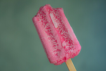 Holding delicious strawberry popsicle with a bite