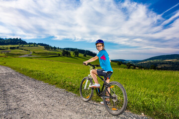 Fototapeta premium Young woman riding a bicycle on country road
