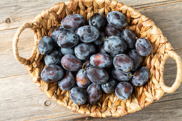 Ripe plum. Lots of plums in a basket on a gray wooden table. Blue plums close-up. Healthy fruits	