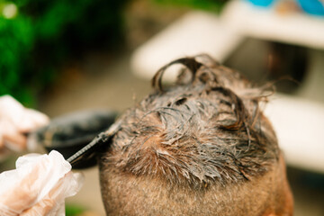 Stylist with hair dye and brush coloring hair