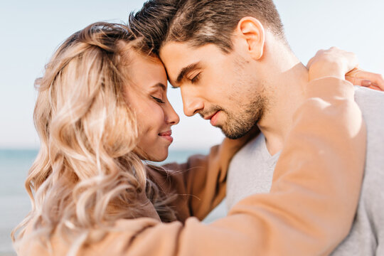 Satisfied man embracing wife outdoor. Portrait of cute blonde girl enjoying date.