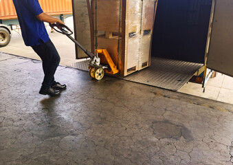 Worker driving forklift loading shipment carton boxes goods on wooden pallet at loading dock from container truck to warehouse cargo storage in freight logistics, transportation industrial, delivery