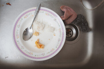 White dirty dish with spoon in sink after eating
