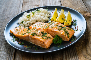 Roasted salmon steaks with lemon, basmati rice and lemon served on wooden table
