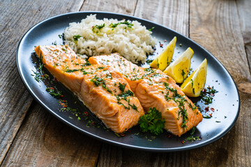 Roasted salmon steaks with lemon, basmati rice and lemon served on wooden table
