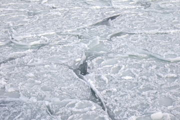 Natural sea ice blocks breaking up against the shore and ice during freezing winter weather. In the background