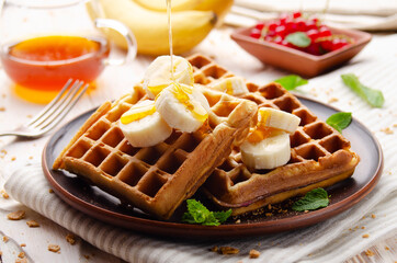 Homemade crispy Belgian waffles served with banana and honey