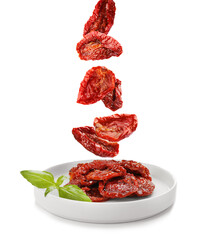 Tasty sun dried tomatoes falling on plate, white background