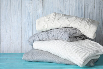 Stack of folded warm sweaters on turquoise wooden table