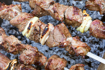 Grilled kebab cooking on metal skewer. Roasted meat cooked at barbecue. BBQ fresh beef meat chop slices. Traditional eastern dish, shish kebab. Grill on charcoal and flame, picnic, street food