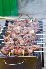Grilled kebab cooking on metal skewer. Roasted meat cooked at barbecue. BBQ fresh beef meat chop slices. Traditional eastern dish, shish kebab. Grill on charcoal and flame, picnic, street food