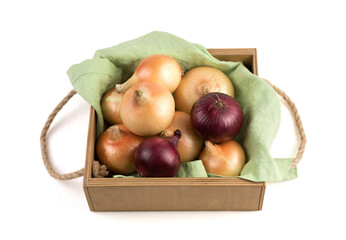 Onions of different varieties in a beautiful wooden packing box on a linen napkin, isolated on a white background. Vegetable background. Concept of natural products.