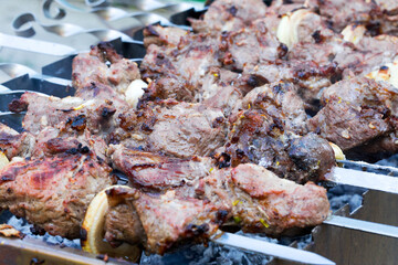 Grilled kebab cooking on metal skewer. Roasted meat cooked at barbecue. BBQ fresh beef meat chop slices. Traditional eastern dish, shish kebab. Grill on charcoal and flame, picnic, street food