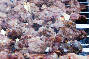 Grilled kebab cooking on metal skewer. Roasted meat cooked at barbecue. BBQ fresh beef meat chop slices. Traditional eastern dish, shish kebab. Grill on charcoal and flame, picnic, street food