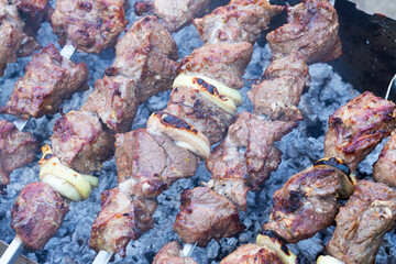 Grilled kebab cooking on metal skewer. Roasted meat cooked at barbecue. BBQ fresh beef meat chop slices. Traditional eastern dish, shish kebab. Grill on charcoal and flame, picnic, street food