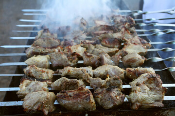 Grilled kebab cooking on metal skewer. Roasted meat cooked at barbecue. BBQ fresh beef meat chop slices. Traditional eastern dish, shish kebab. Grill on charcoal and flame, picnic, street food