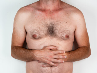 Young muscular fitness man holding his stomach suffering strong abdominal pain. Isolated on neutral background. In stomachache, digestive problems and health care issues.